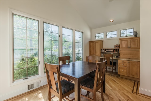 dining room featuring plenty of natural light, vaulted ceiling, light wood-type flooring, and visible vents