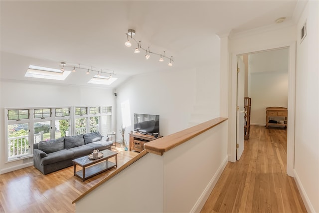living room with baseboards, light wood-type flooring, lofted ceiling with skylight, and visible vents