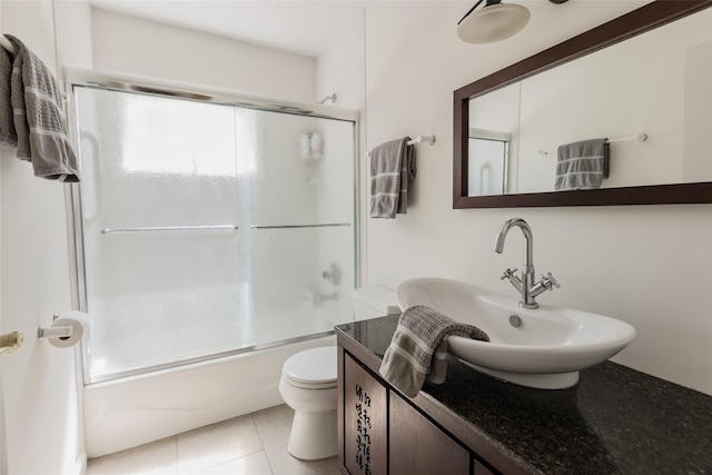 bathroom with toilet, enclosed tub / shower combo, tile patterned flooring, and vanity
