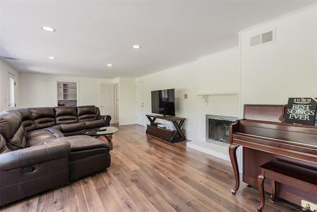 living area featuring a brick fireplace, recessed lighting, visible vents, and wood finished floors