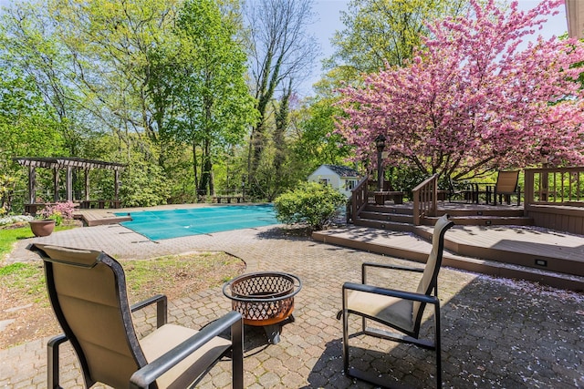 view of pool with a deck, a patio area, an outdoor fire pit, a pergola, and a covered pool