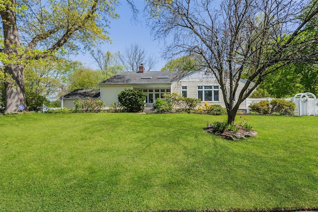 back of property featuring a shingled roof, fence, a yard, and a chimney