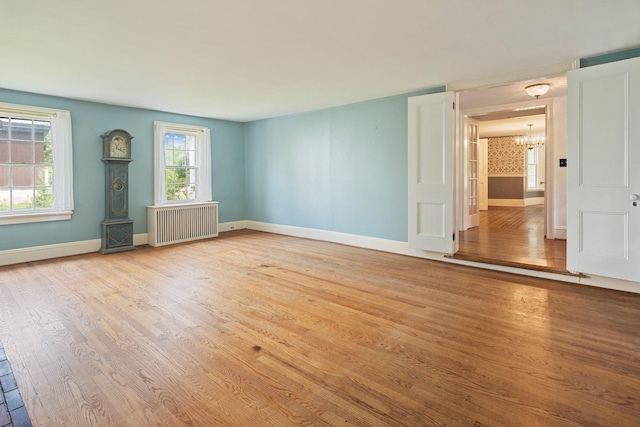 27 Bedford Rd, Pleasantville, NY 10570 - empty room with radiator heating unit, a chandelier, and light wood-style flooring