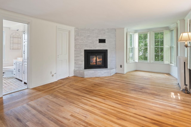 27 Bedford Rd, Pleasantville, NY 10570 - unfurnished living room with radiator heating unit, a fireplace, and light wood-style floors
