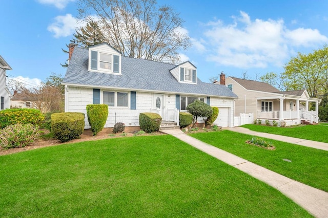 cape cod-style house featuring a chimney, covered porch, roof with shingles, a front lawn, and an attached garage