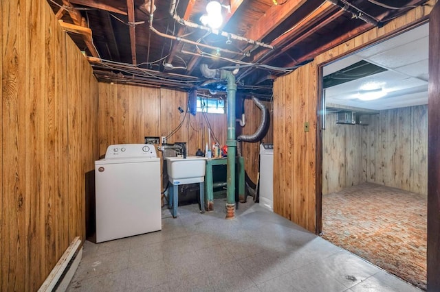 below grade area featuring wooden walls, a baseboard radiator, and washing machine and dryer