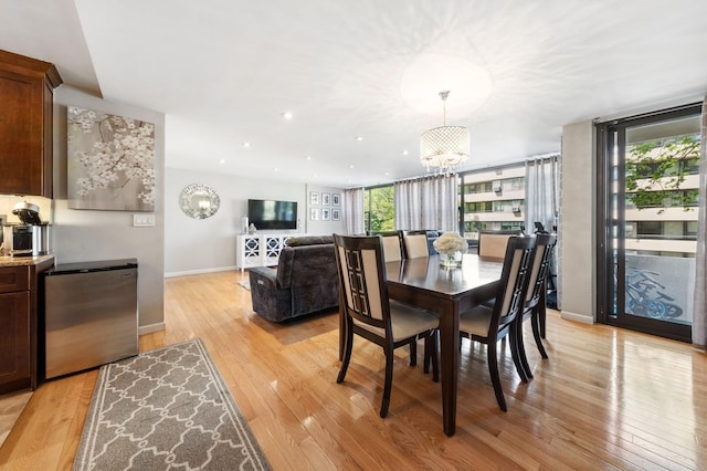 dining space featuring an inviting chandelier, baseboards, and light wood finished floors