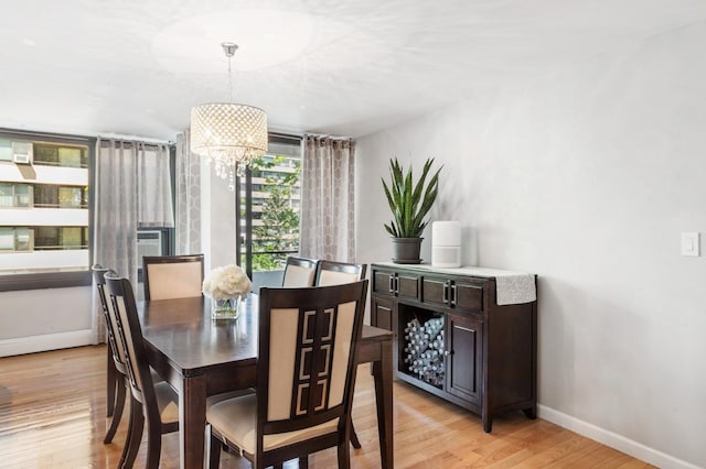 dining area featuring baseboards, light wood-style flooring, and a chandelier