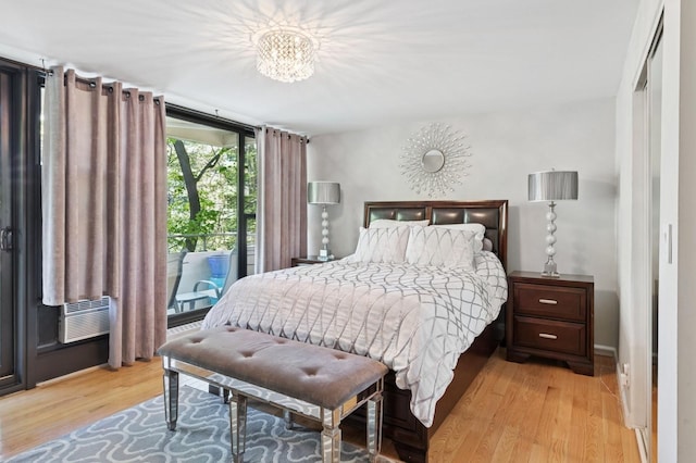 bedroom with light wood-style floors, access to outside, and an inviting chandelier
