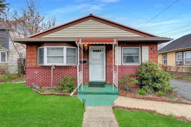 view of front of house with brick siding, a front lawn, fence, and cooling unit