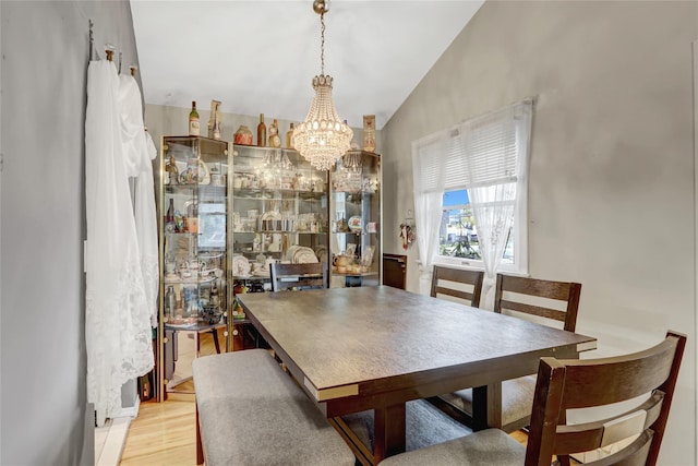dining area featuring lofted ceiling, light wood-style flooring, and a chandelier