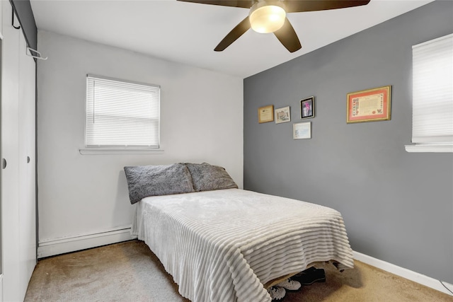 bedroom featuring carpet floors, multiple windows, baseboard heating, and a ceiling fan