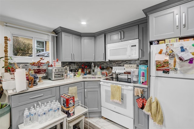 kitchen with white appliances, a sink, gray cabinets, and tasteful backsplash
