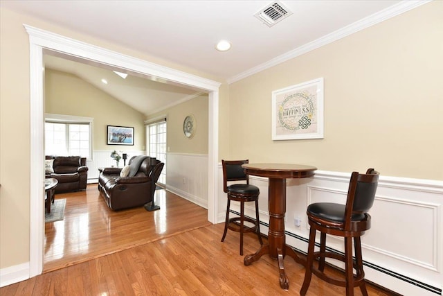 interior space featuring a baseboard radiator, visible vents, a wainscoted wall, ornamental molding, and wood finished floors