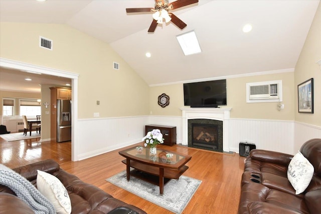 living room with visible vents, a wainscoted wall, and vaulted ceiling with skylight