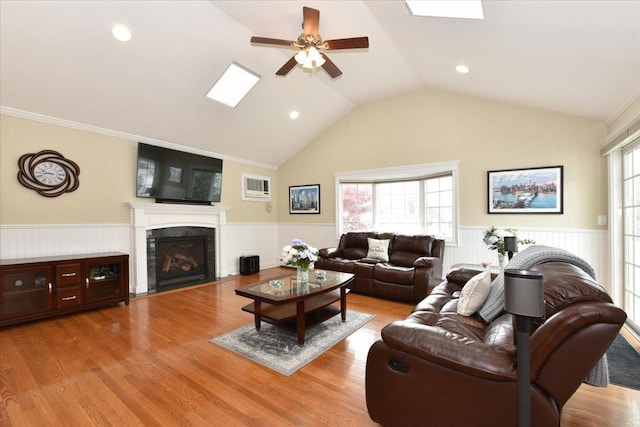 living area with a wainscoted wall, ceiling fan, a fireplace, and lofted ceiling