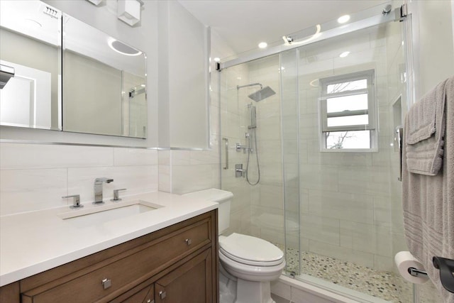 full bath with tile walls, a stall shower, toilet, and vanity