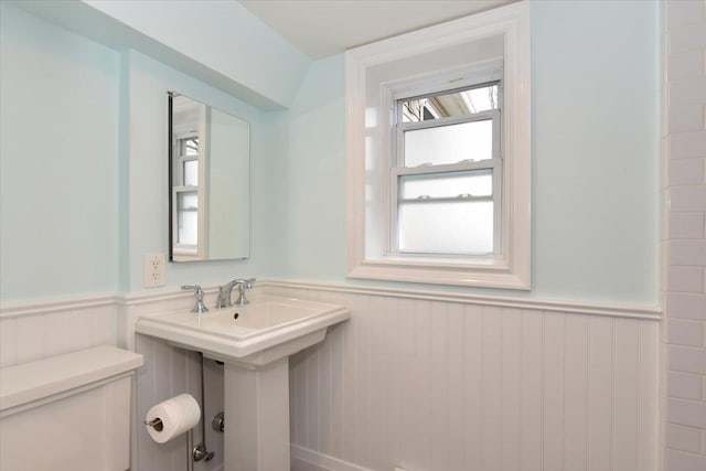 half bath with toilet and a wainscoted wall