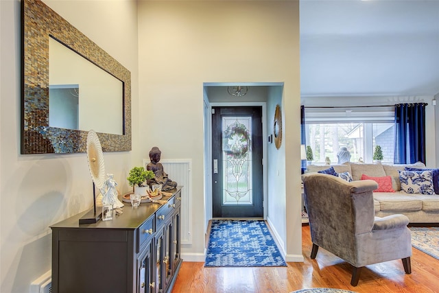 foyer featuring light wood-type flooring, baseboards, a high ceiling, and a chandelier