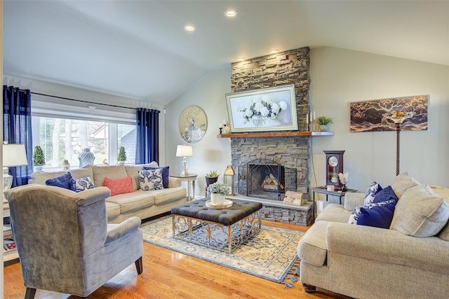 living room featuring wood finished floors, recessed lighting, lofted ceiling, and a stone fireplace