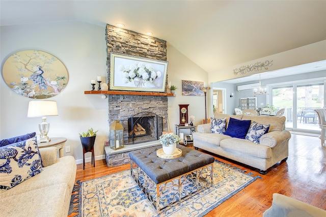 living area featuring an inviting chandelier, high vaulted ceiling, a stone fireplace, and wood finished floors