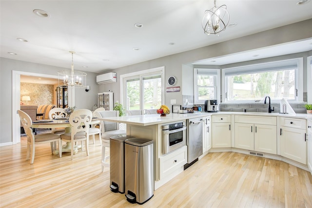 kitchen with a notable chandelier, a healthy amount of sunlight, light wood finished floors, and a wall mounted air conditioner
