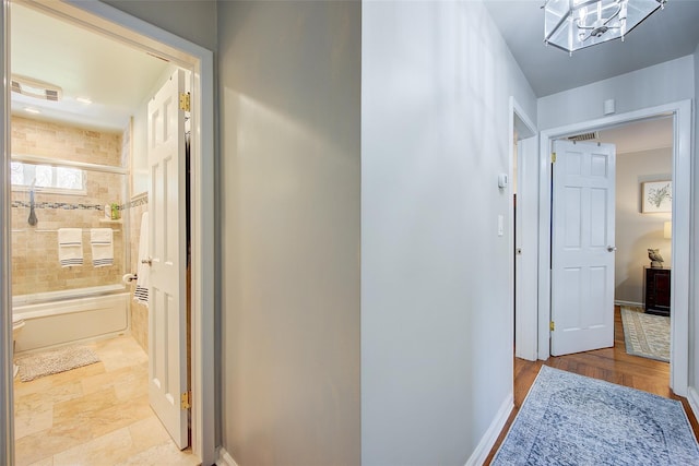 hallway featuring baseboards and visible vents