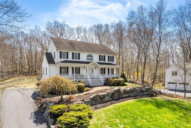 view of front of property featuring a porch, a front lawn, and roof with shingles