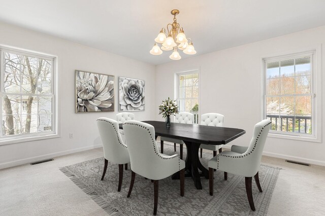 dining room featuring visible vents, baseboards, a notable chandelier, and light carpet