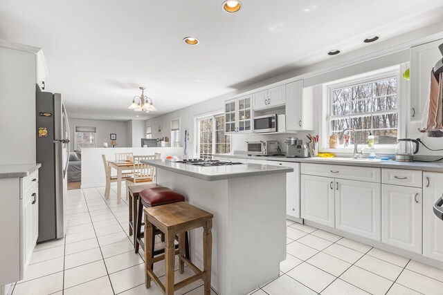 kitchen featuring a kitchen breakfast bar, a kitchen island, appliances with stainless steel finishes, light tile patterned floors, and an inviting chandelier