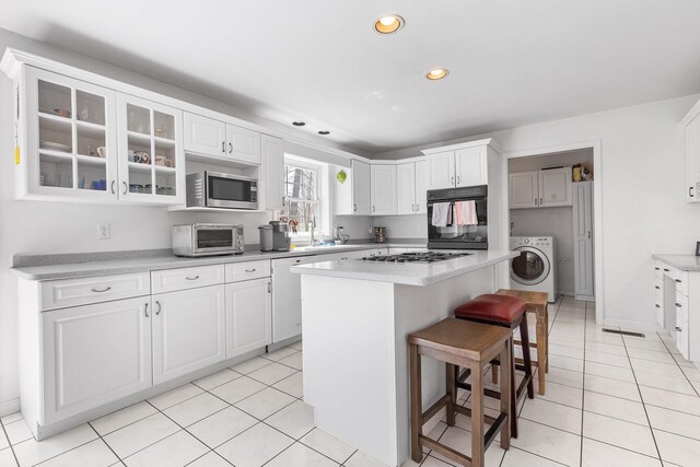 kitchen with a toaster, stainless steel microwave, washer / dryer, black oven, and recessed lighting
