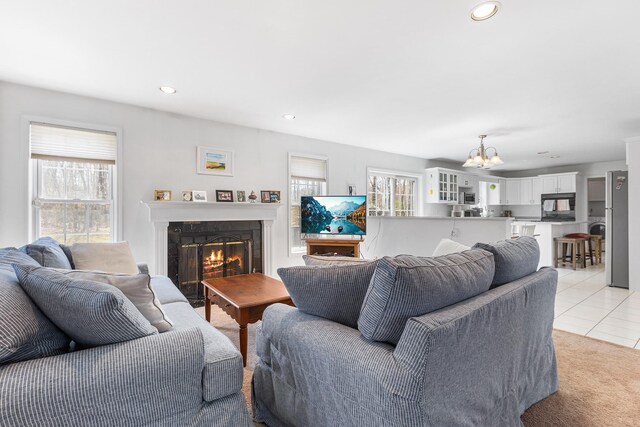 living room with an inviting chandelier, plenty of natural light, light tile patterned floors, and a premium fireplace