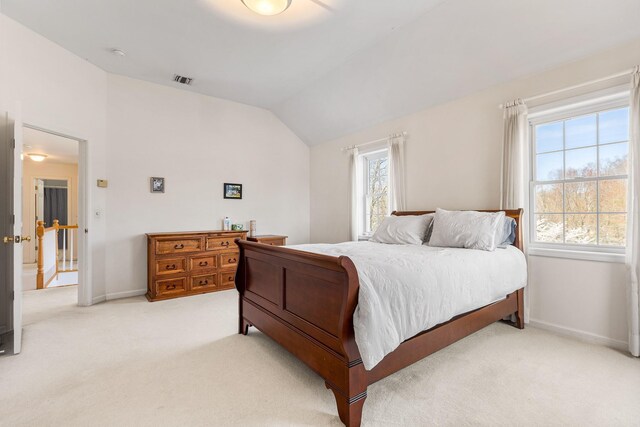 bedroom with baseboards, visible vents, vaulted ceiling, and light colored carpet