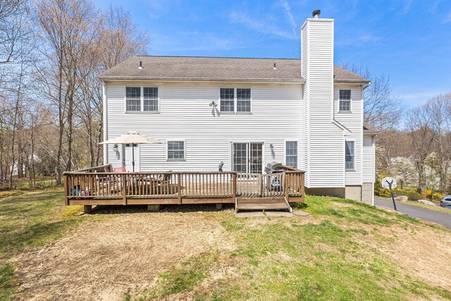 back of property featuring a lawn, a wooden deck, and a chimney