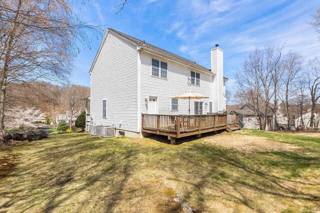 rear view of property with a yard, a deck, a chimney, and central air condition unit