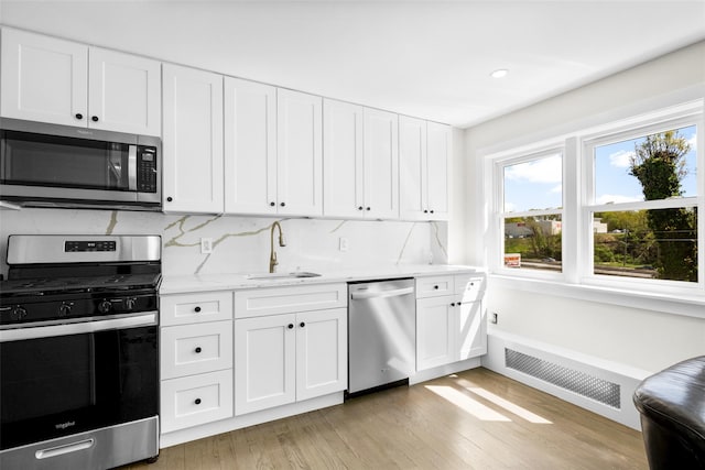120 Loomis Ave, Yonkers, NY 10704 - kitchen with stainless steel appliances, a sink, light wood-type flooring, white cabinetry, and backsplash