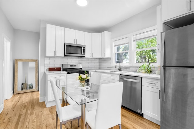 120 Loomis Ave, Yonkers, NY 10704 - kitchen featuring stainless steel appliances, white cabinetry, tasteful backsplash, and light wood-style flooring