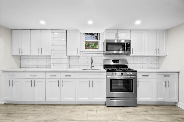 120 Loomis Ave, Yonkers, NY 10704 - kitchen featuring appliances with stainless steel finishes, a sink, white cabinetry, decorative backsplash, and recessed lighting