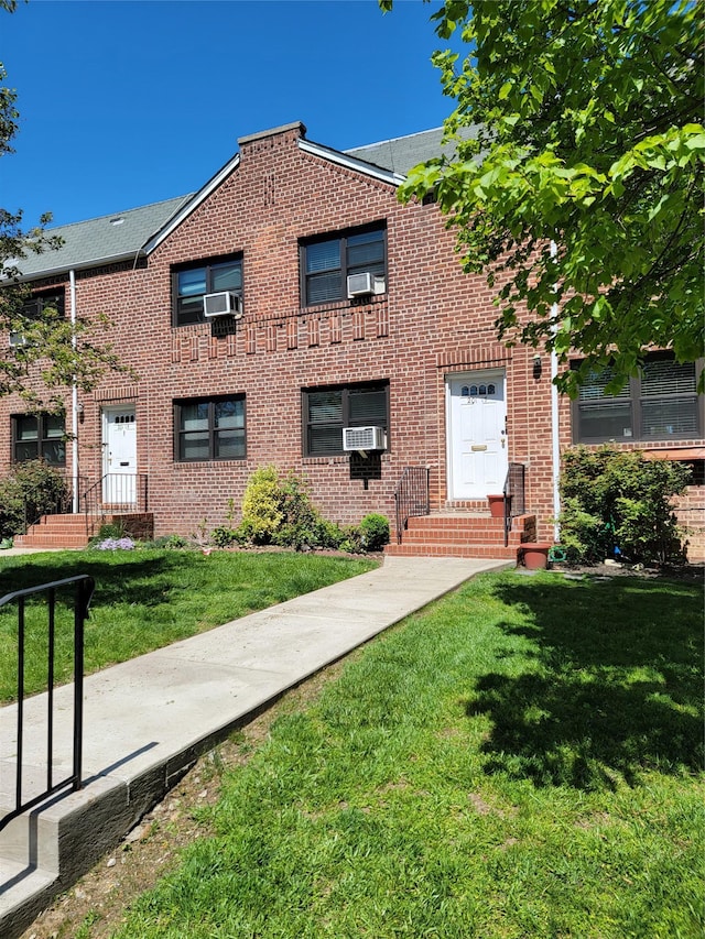 multi unit property with brick siding, a front yard, and cooling unit