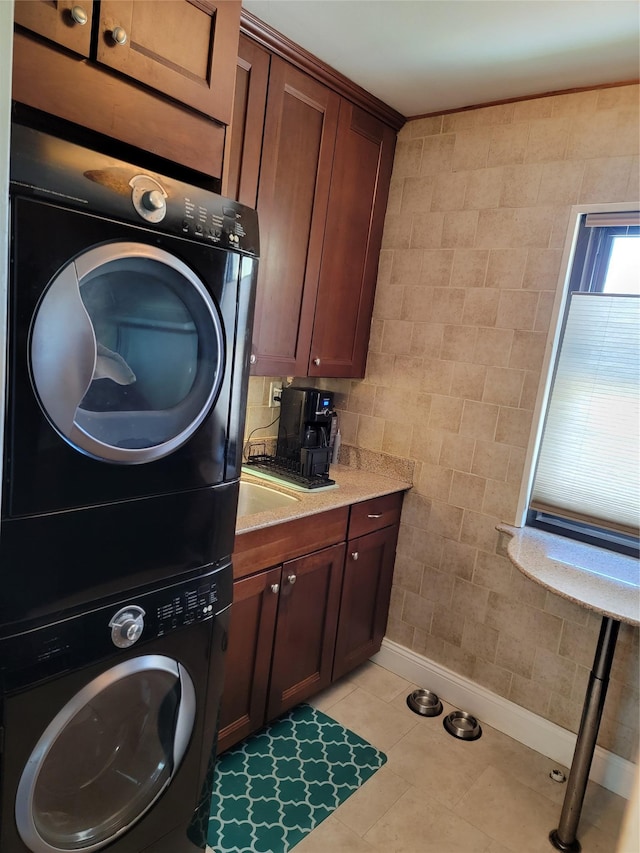 laundry area with laundry area, tile walls, baseboards, stacked washer / drying machine, and light tile patterned floors