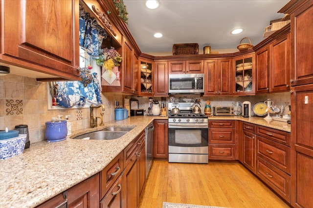 kitchen featuring appliances with stainless steel finishes, a sink, tasteful backsplash, light stone counters, and recessed lighting