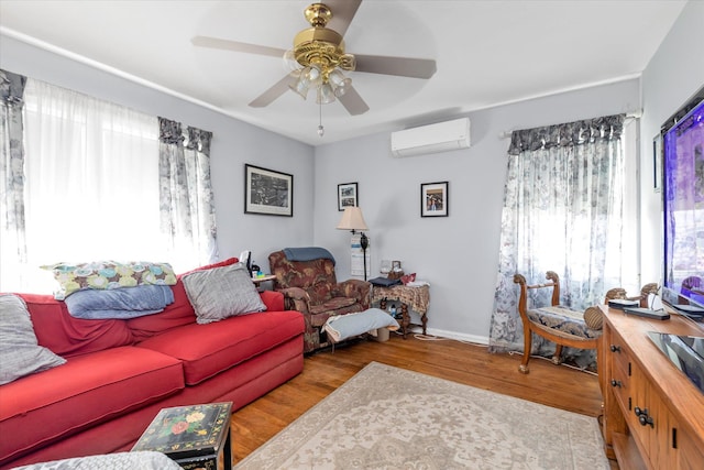 living area with a wall mounted AC, wood finished floors, ceiling fan, and baseboards