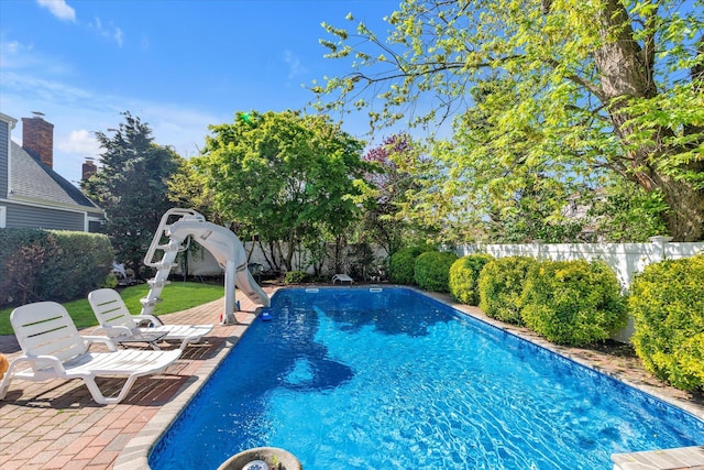 view of pool with a water slide and a fenced backyard