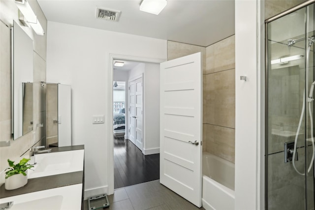 ensuite bathroom with double vanity, a washtub, visible vents, an enclosed shower, and ensuite bath