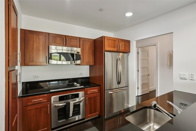 kitchen featuring a sink, dark countertops, stainless steel appliances, and recessed lighting