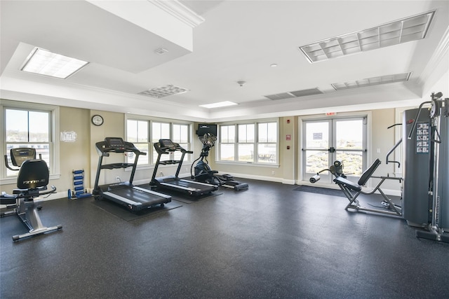 workout area with baseboards, ornamental molding, a tray ceiling, and visible vents