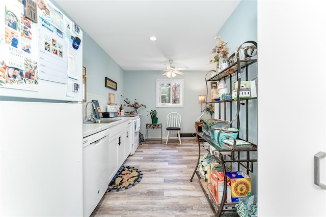 kitchen with a sink, ceiling fan, light wood-style flooring, white cabinetry, and white appliances