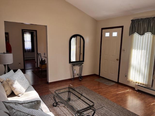 foyer with wood finished floors, a baseboard heating unit, baseboard heating, baseboards, and lofted ceiling