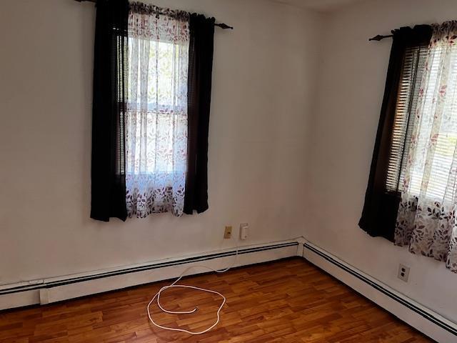 unfurnished room featuring a baseboard radiator and wood finished floors