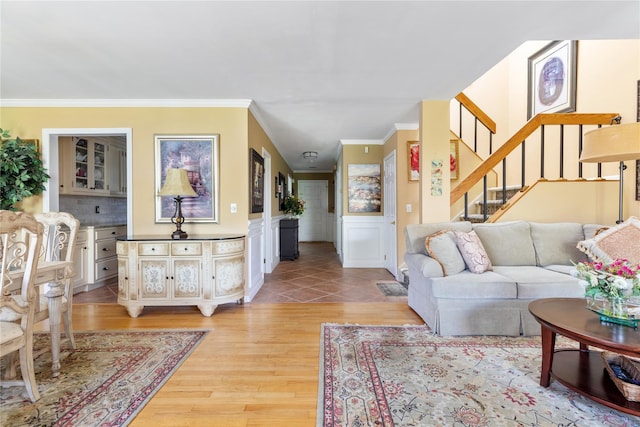 living area featuring crown molding, wainscoting, stairs, and light wood-style flooring
